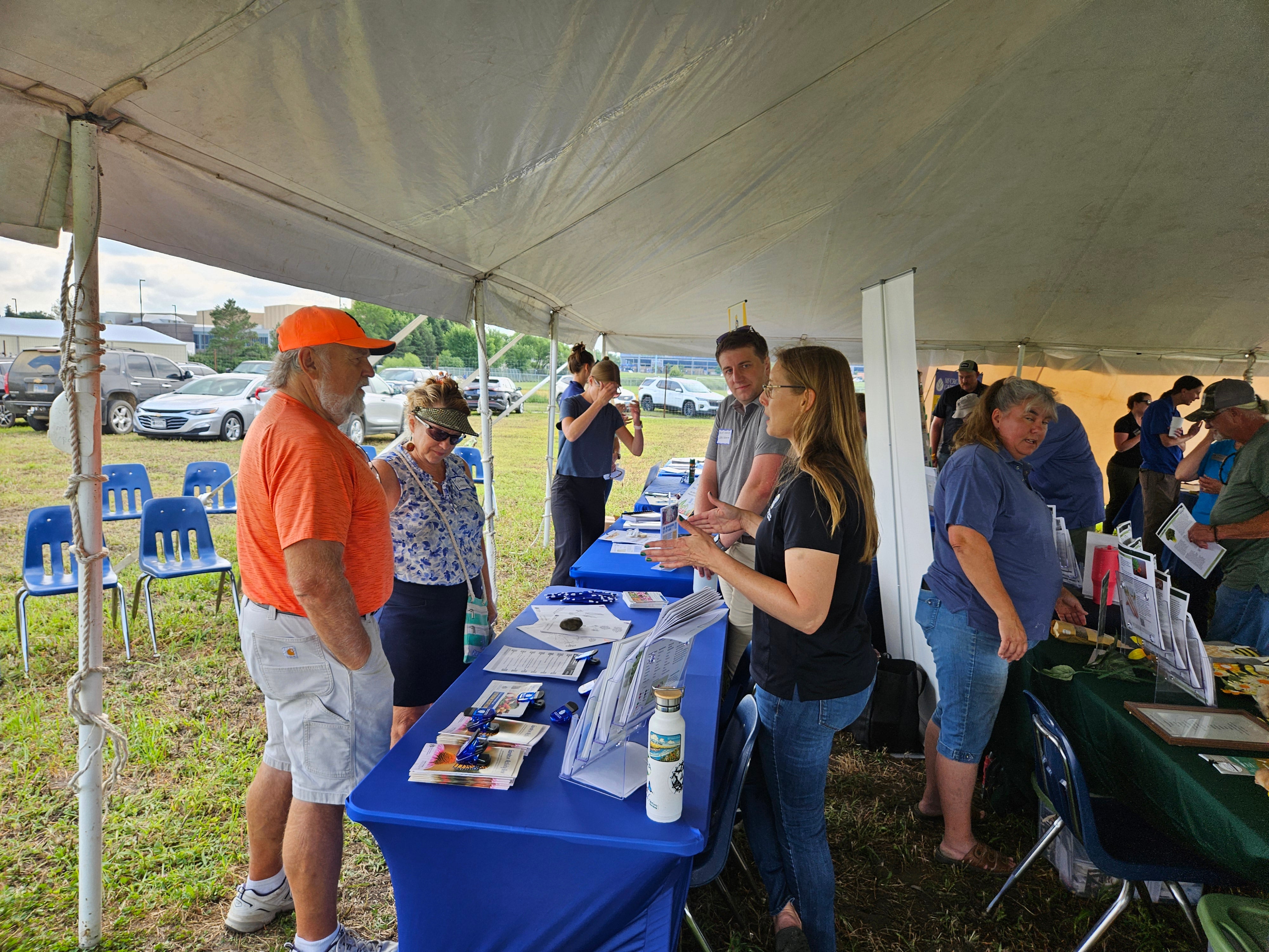 People look at information at tables inside a tent