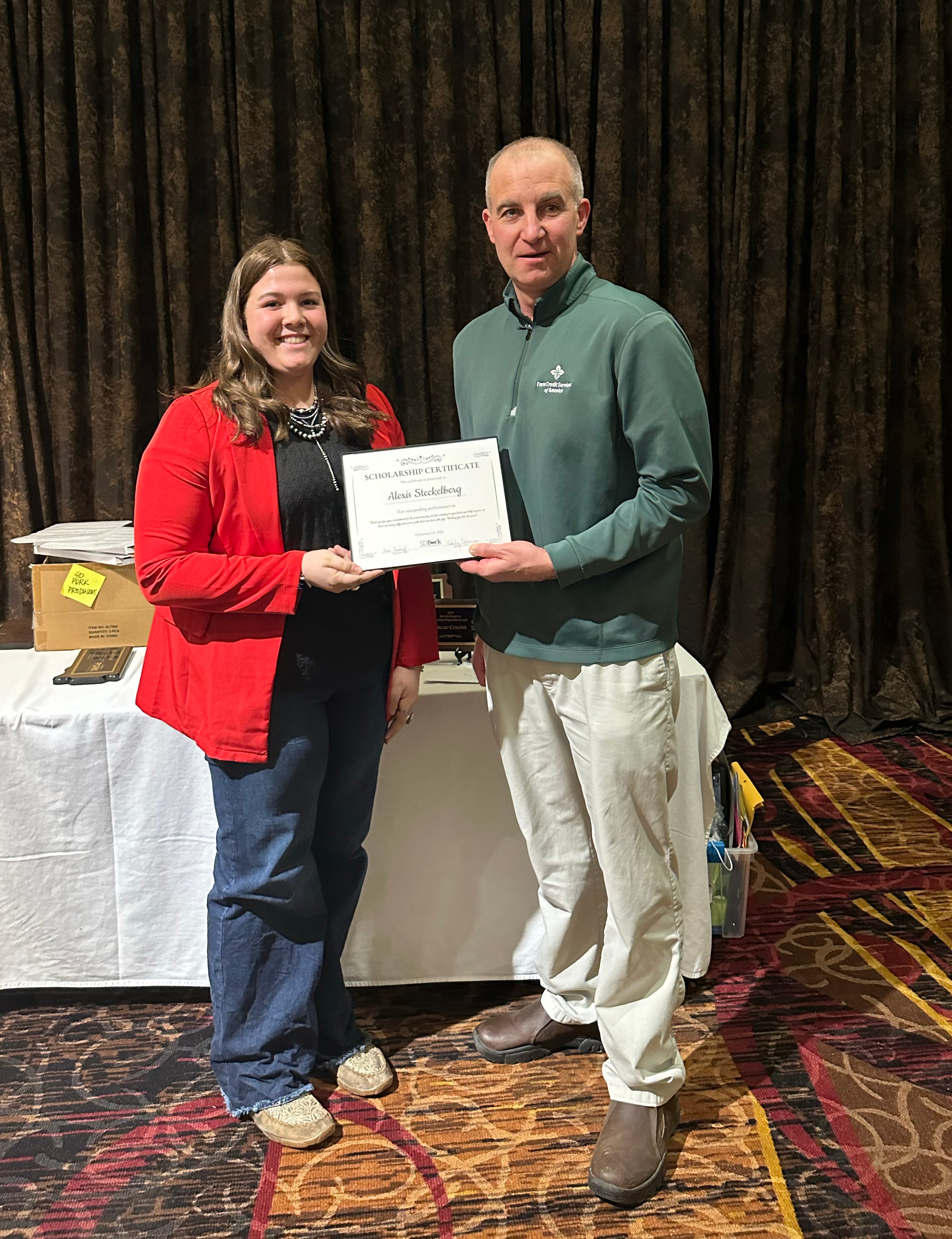 A girl in a red jacket receives a scholarship certificate