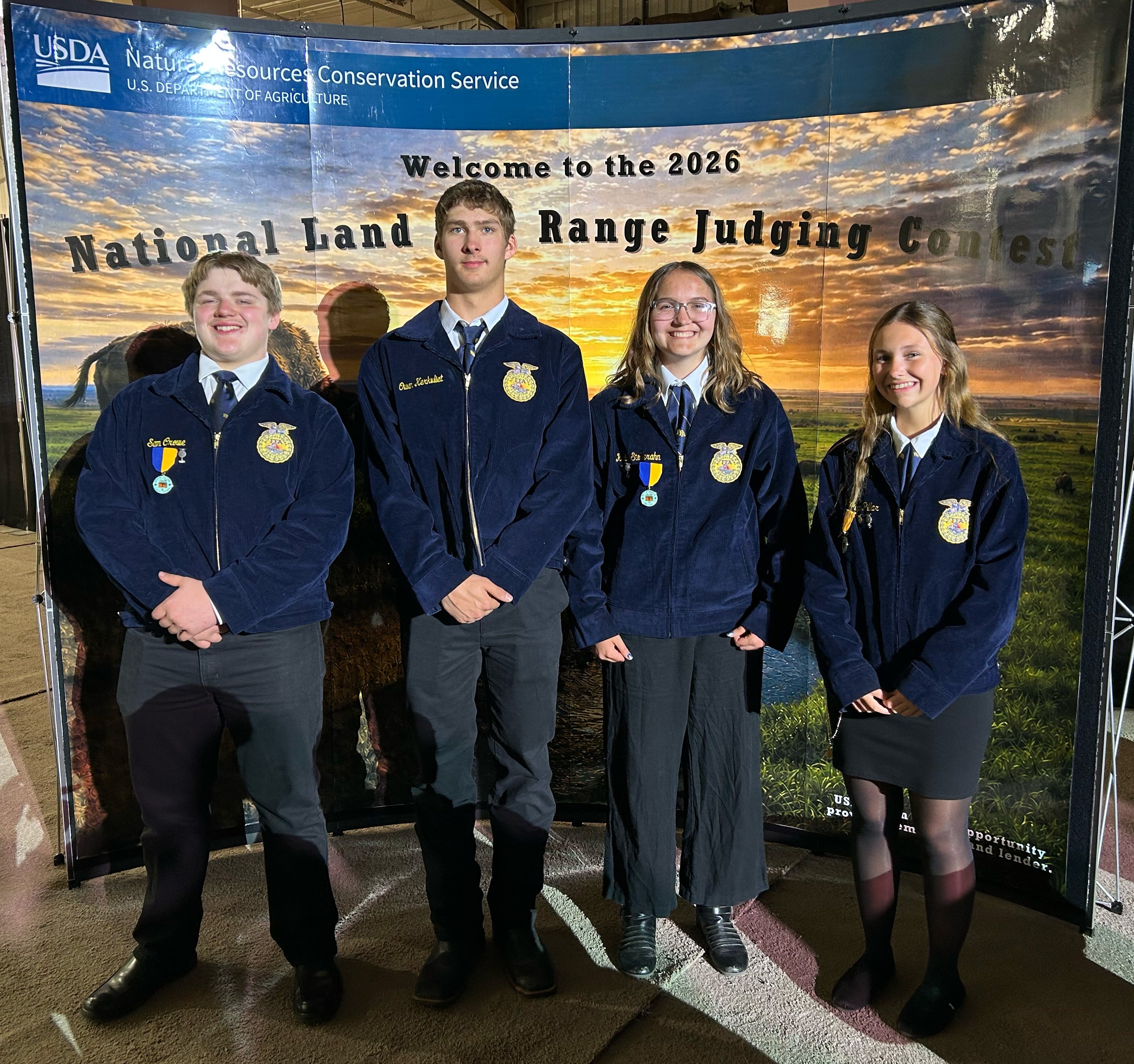 Four youth in matching FFA jackets smile for the camera