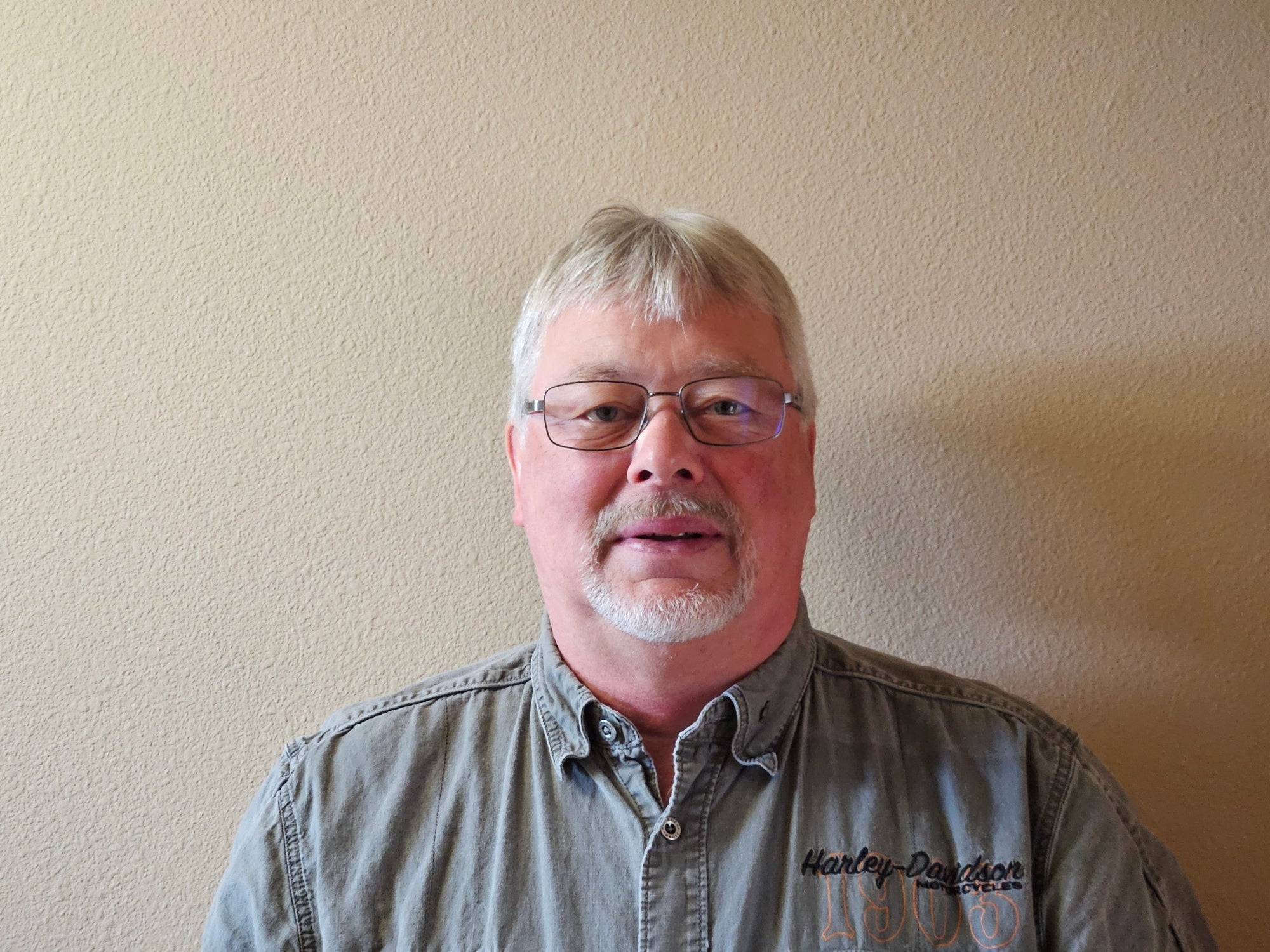 A man with light hair and a mustache smiles for a photo