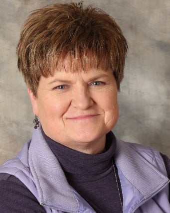 A woman with short brown hair smiles for a photo