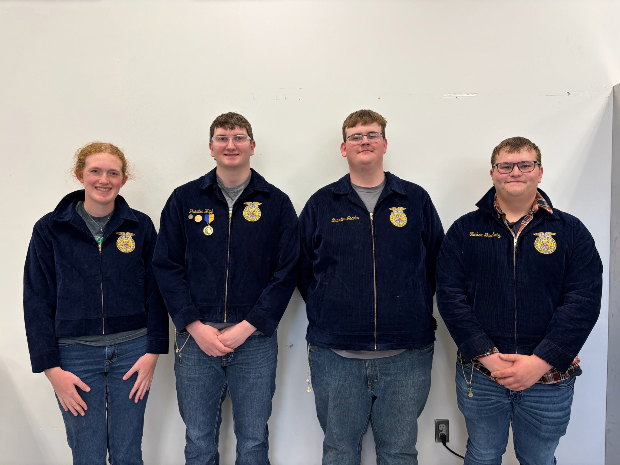 Four people in matching FFA jackets smile for the camera