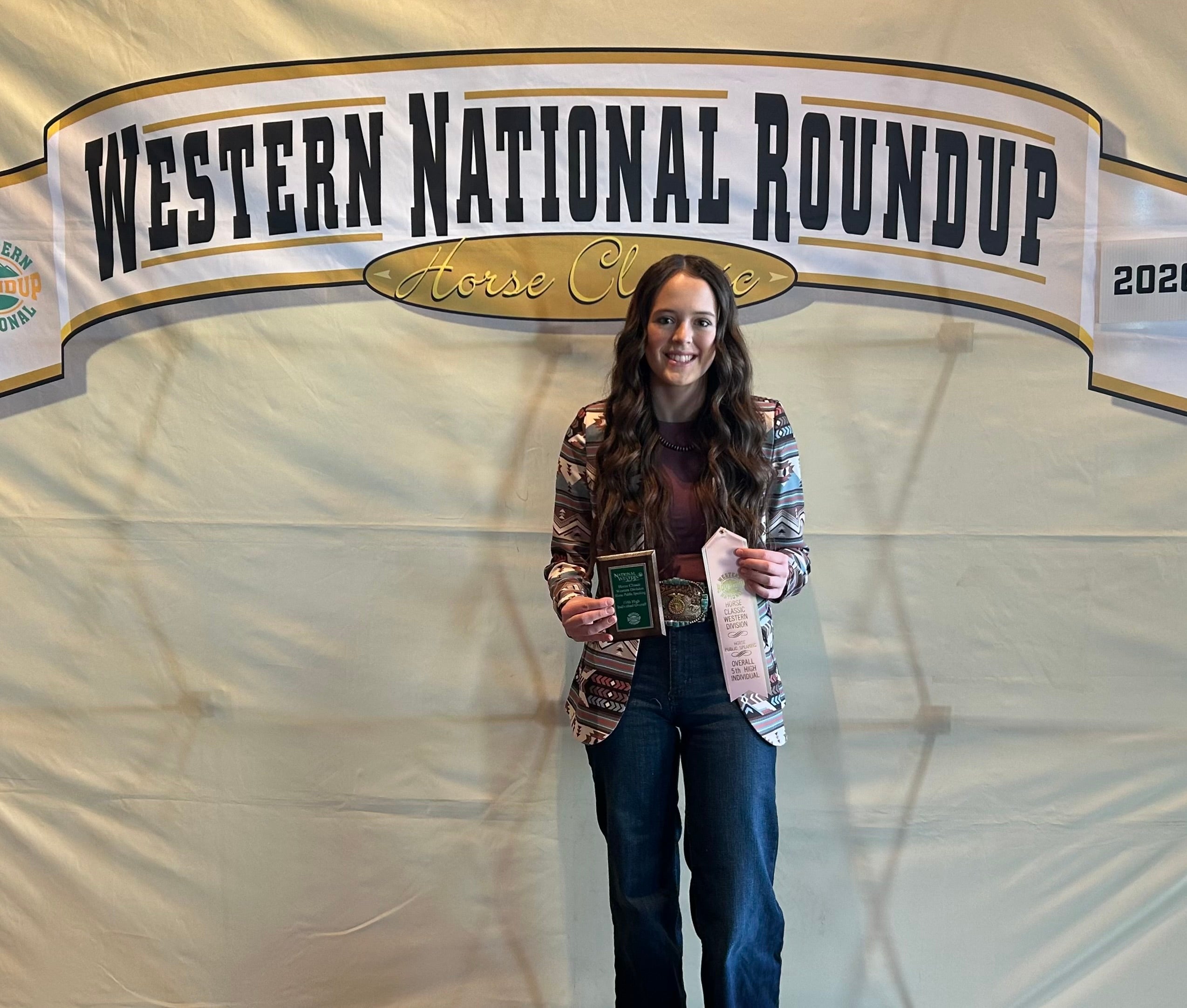 A youth holds up a light pink ribbon and an award plaque