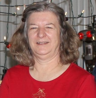 A woman in a red shirt smiles for the camera