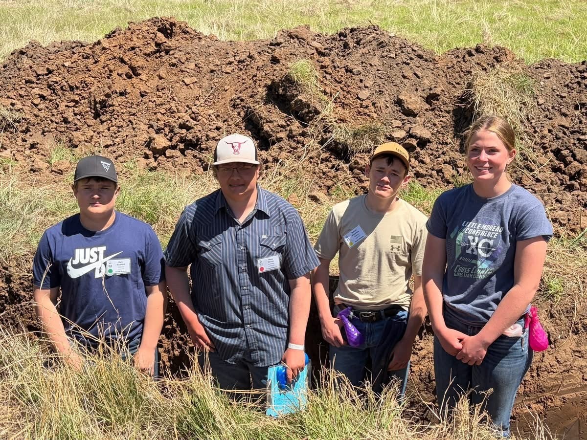 Four youth stand outside in a soil dugout