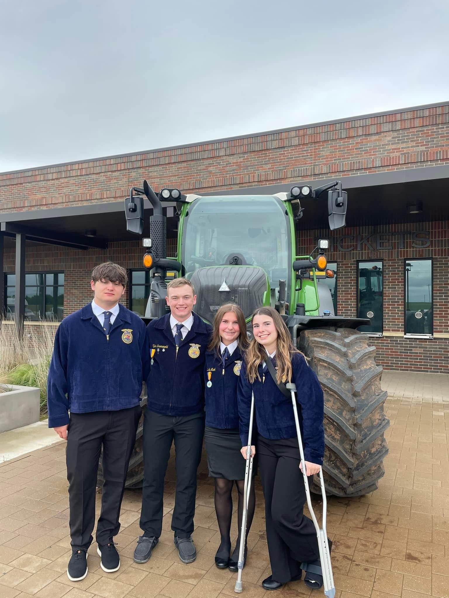 Tri-Valley FFA Land team smiles at the camera in front of a tractor