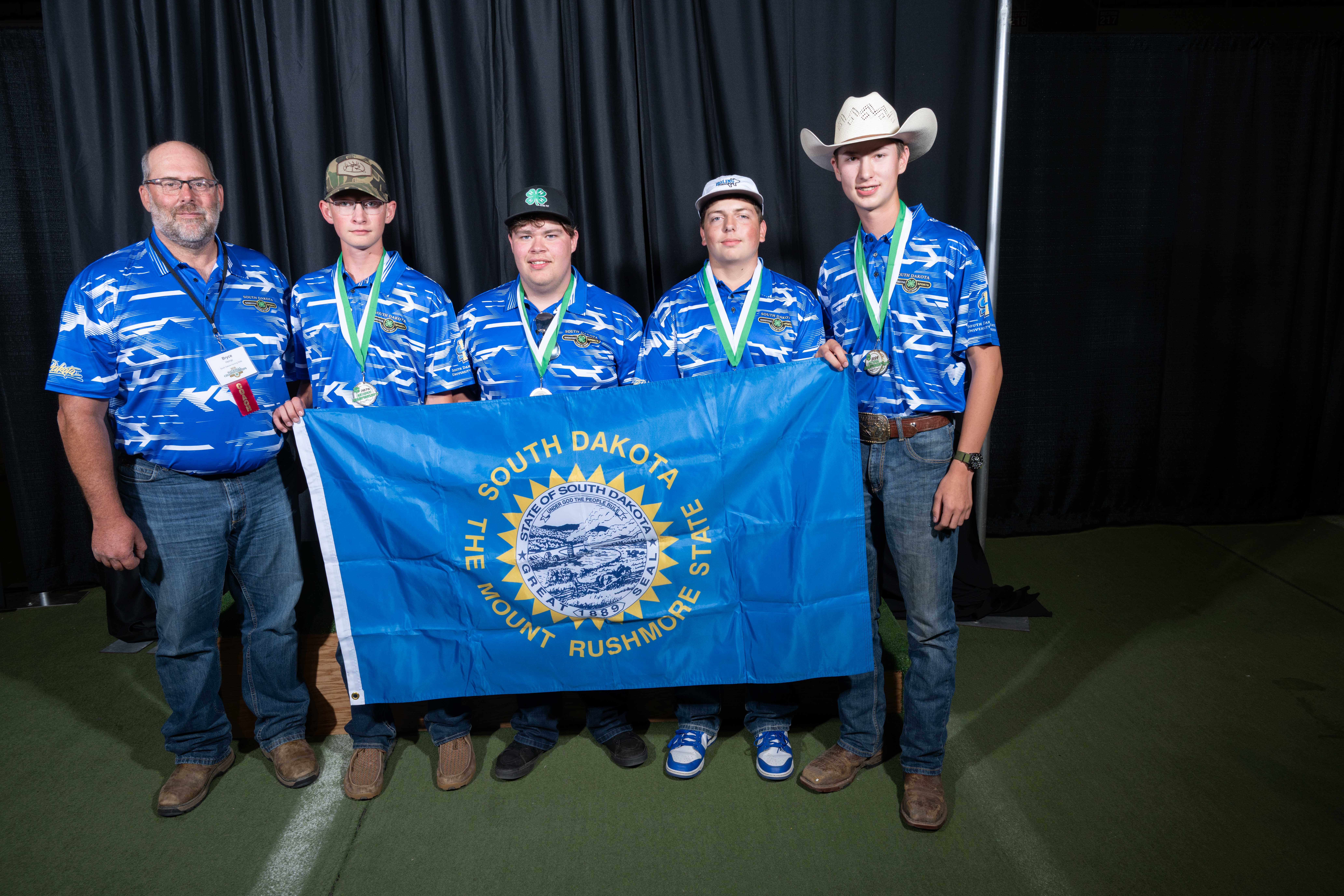 A group of boys smiling while holding a South Dakota state flag