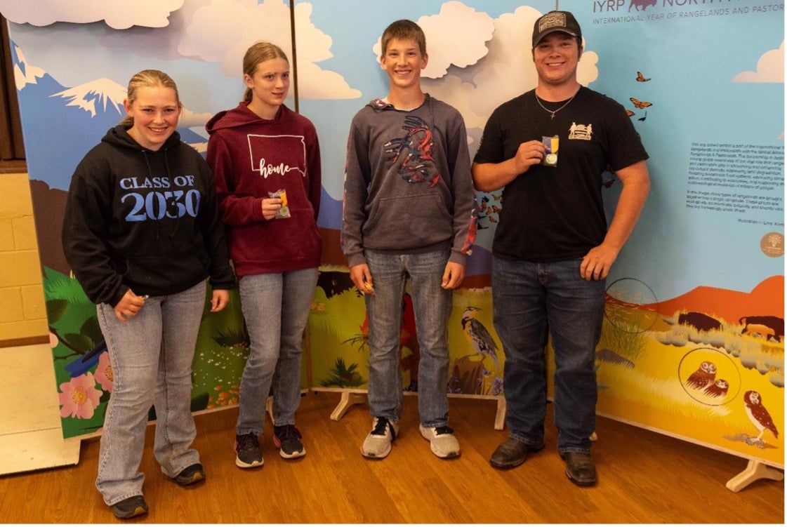 Four teenagers smile with small medals