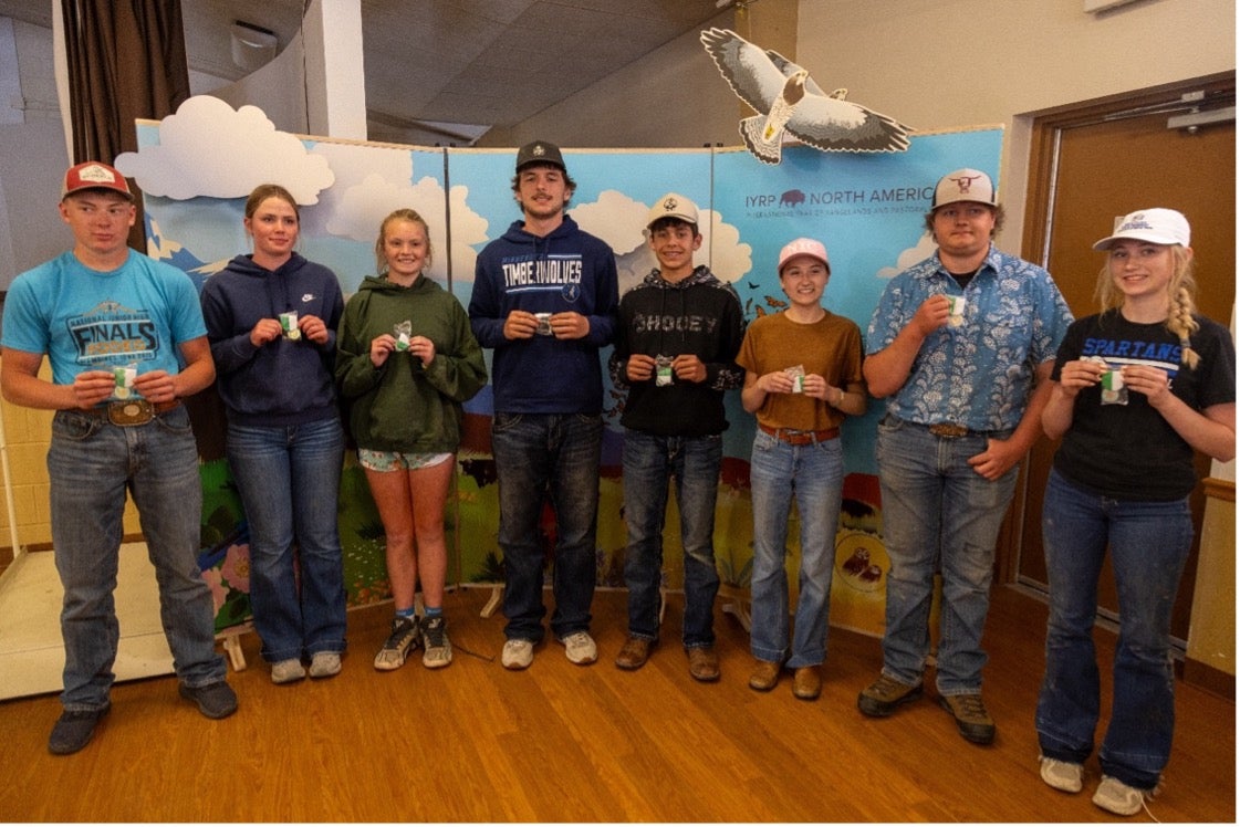 Eight youth smile holding up small green and white medals