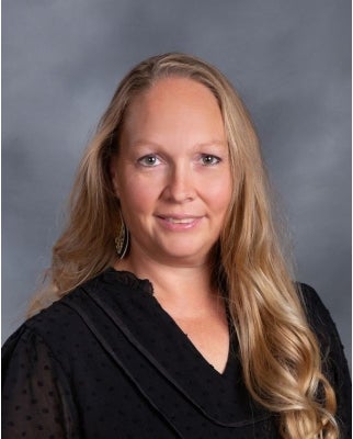 A woman with long blond hair smiles for a photo