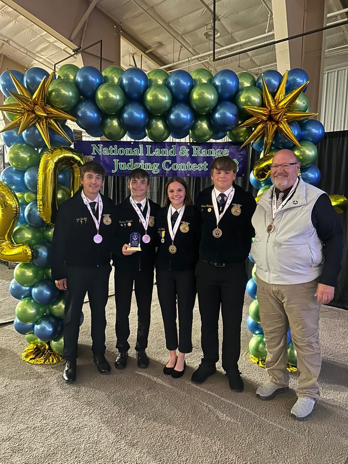 Four youth and their coach smile with fourth-place medals and a plaque