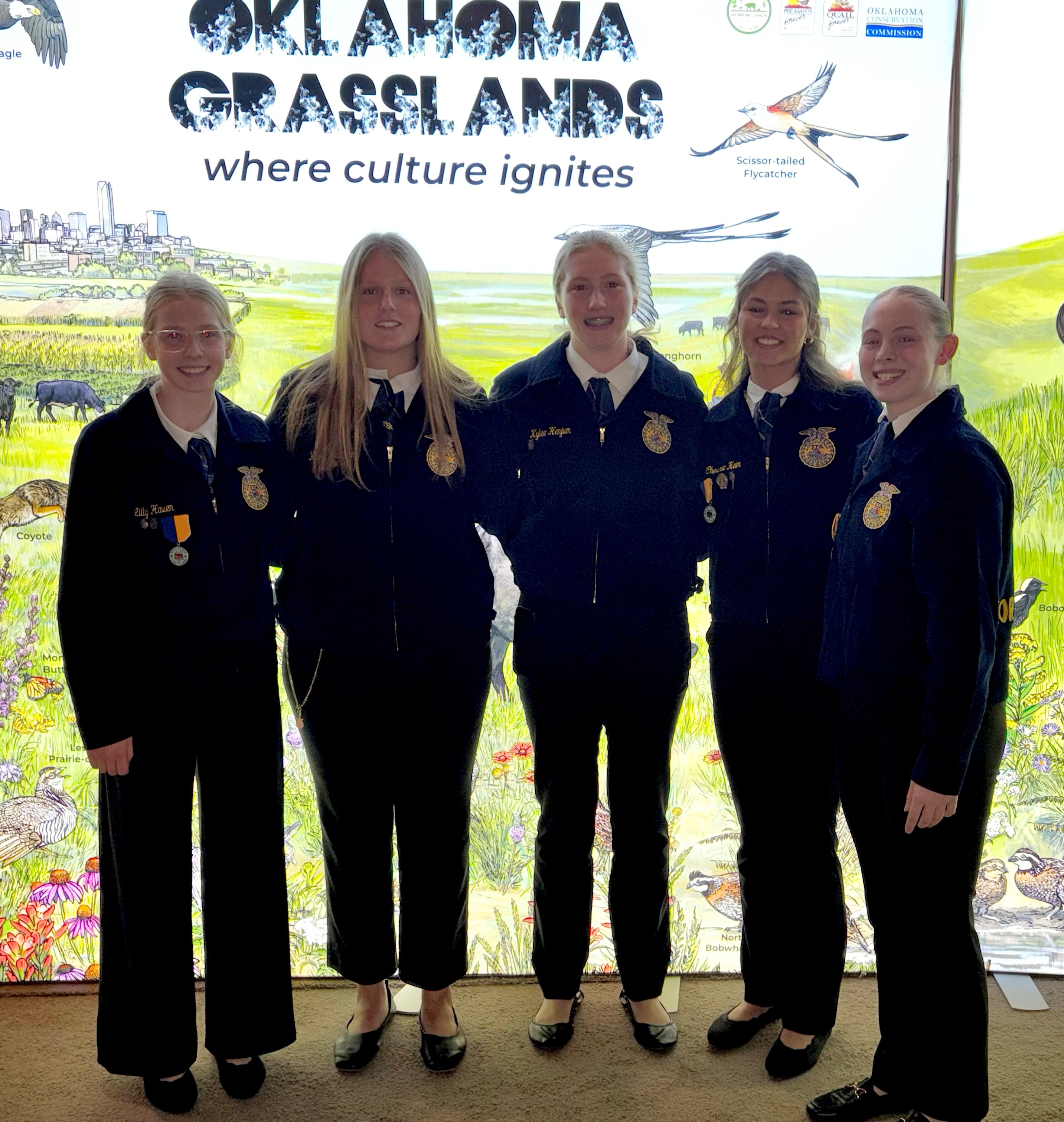 Five teenage girls in matching FFA jackets smile for the camera