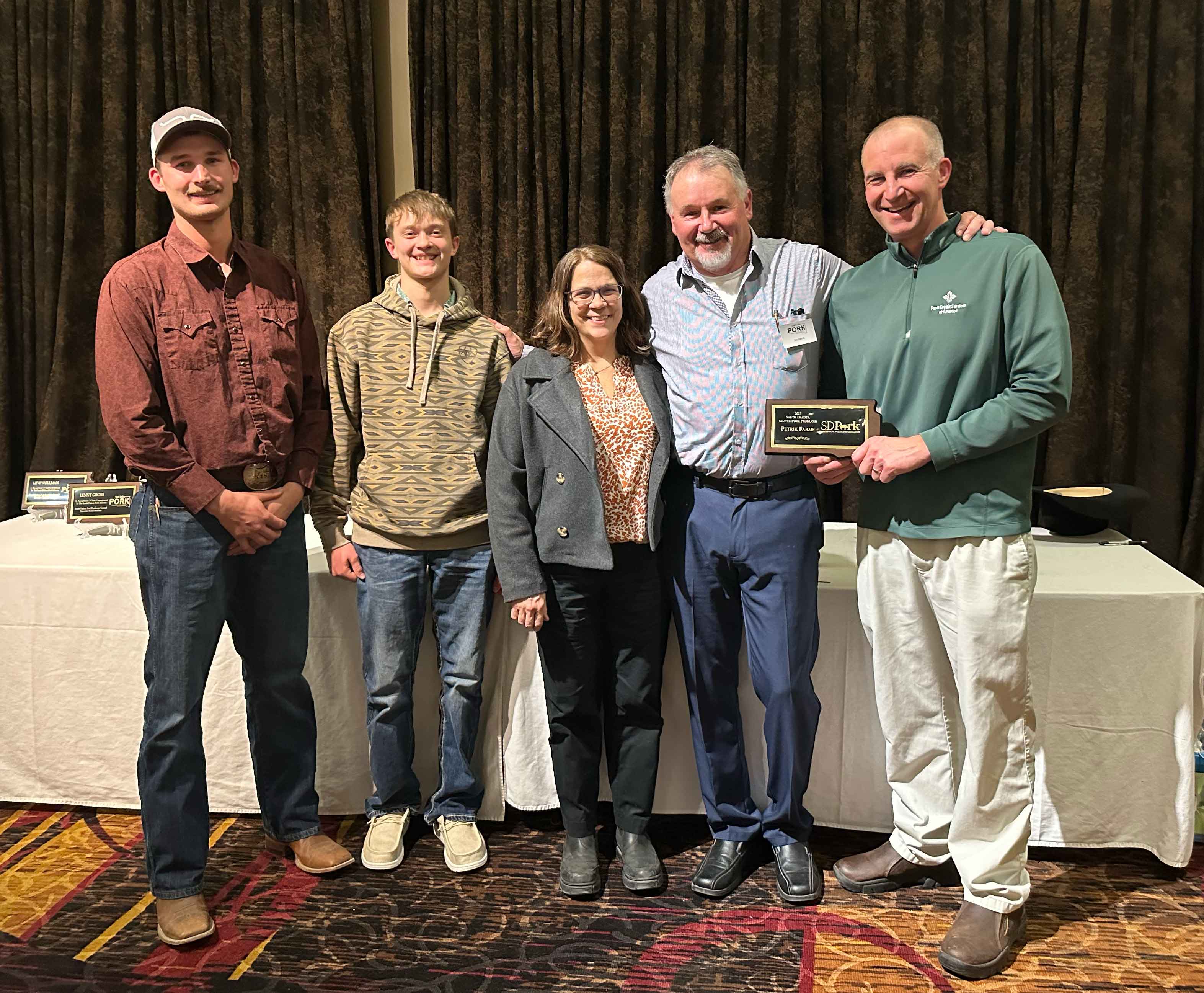 A family smiles while receiving a Master Pork Producers plaque