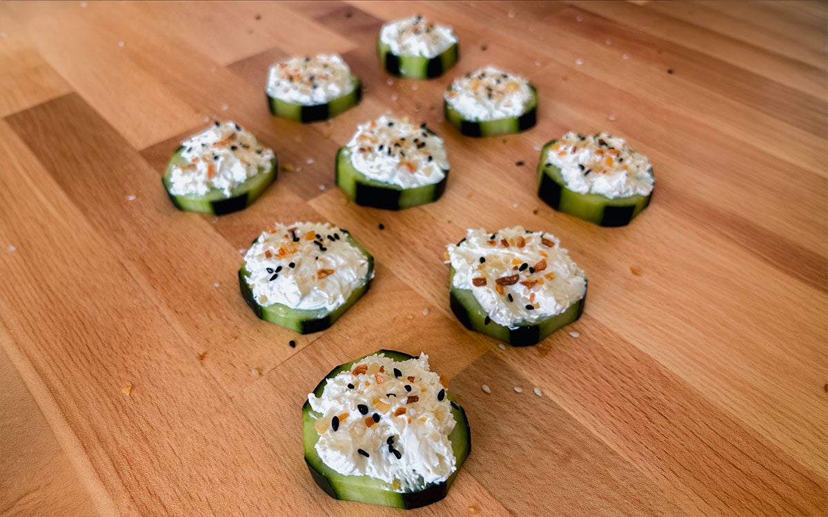 Several cucumber bites snacks arranged on a cutting board.
