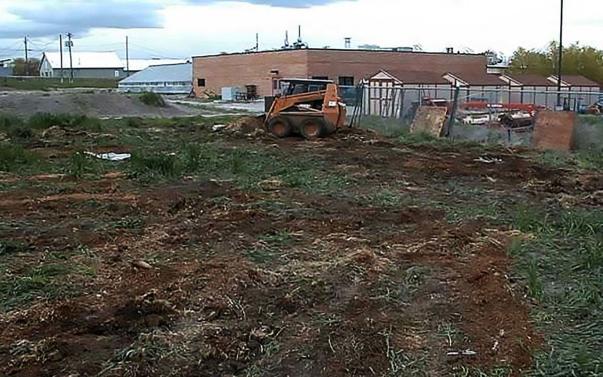Skidloader outside being used to turn compost pile.