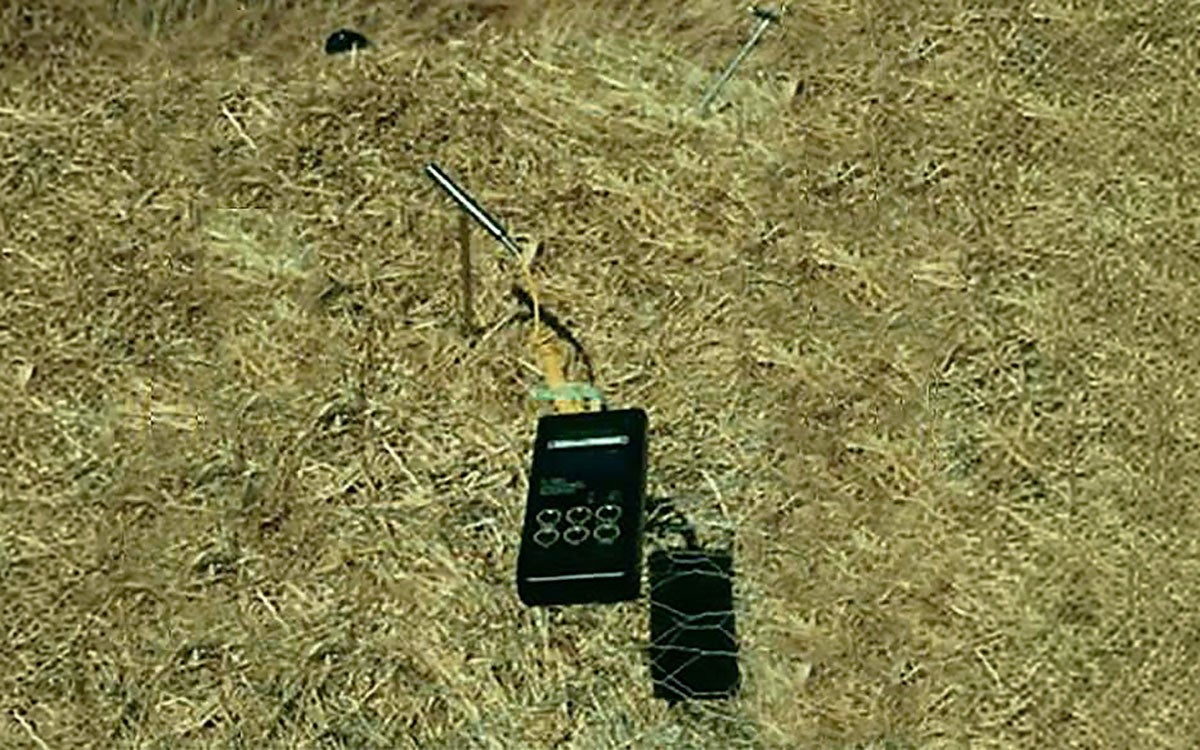 Stainless steel thermometer attached to a digital reader on a compost pile.