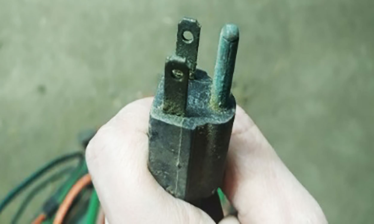 Extension cord plug head with significant corrosion on its prongs.