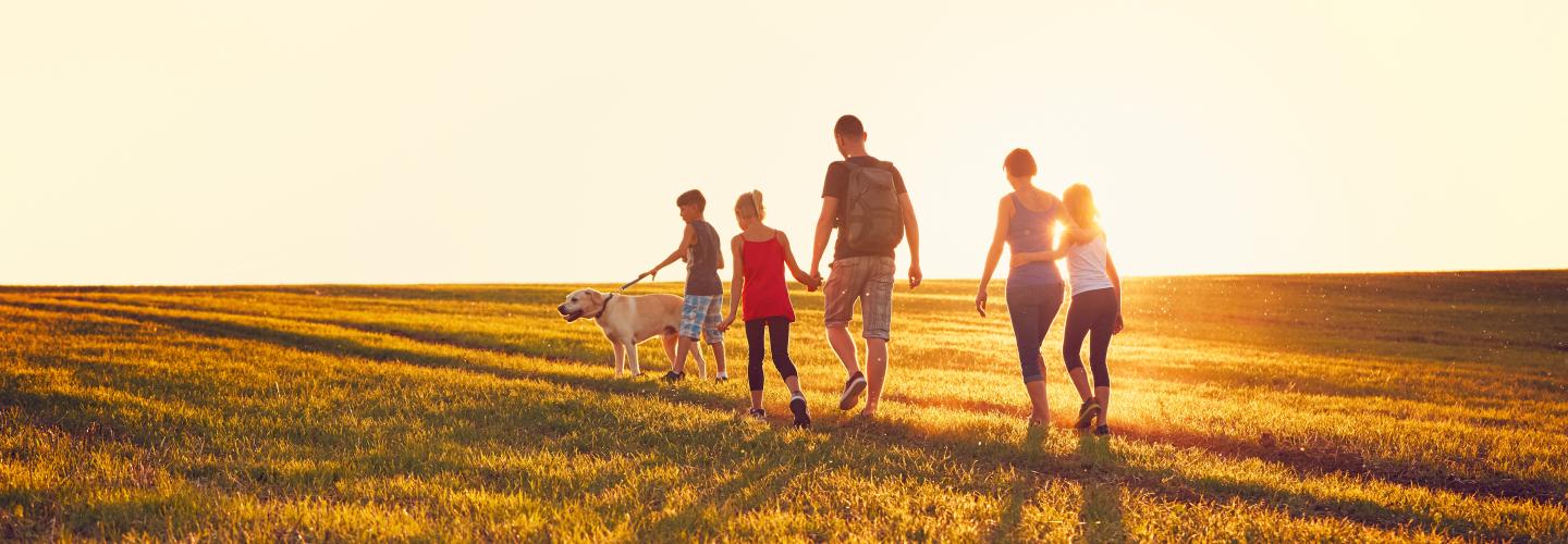 a dad and mom with three children and a yellow lab walking through short grass