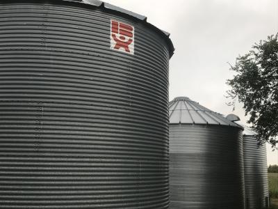 Two large, grey grain bins