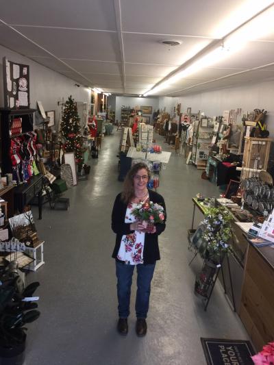 a woman standing in the isle of her store holding flowers