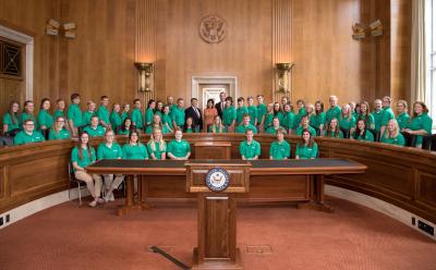 large group of 4-H youth posing for a photo with U.S. government officials inside a governmental chamber