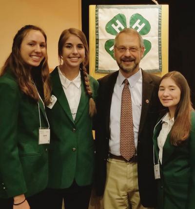 three female 4-H youth standing with and older adult male official