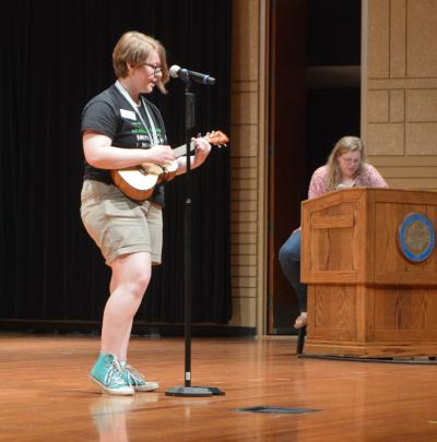 female 4-H youth performing on stage with a ukulele