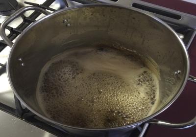 Sap being boiled inside a large pot atop a stove