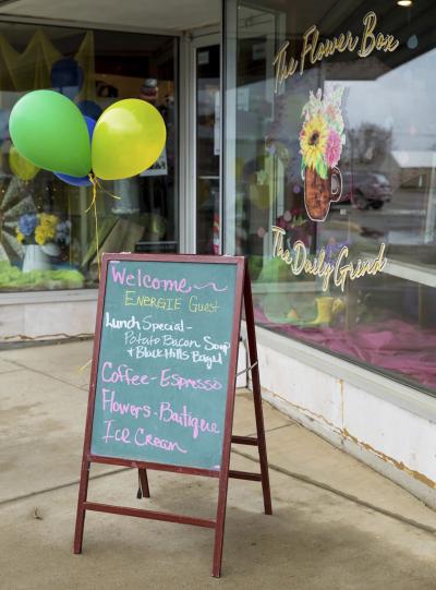 A chalkboard sign outside a local flower and coffee shop welcoming Energize Conference attendees.