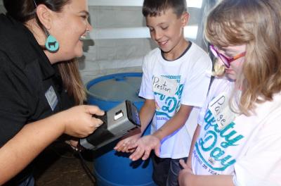 a woman demonstrating a black light to two children.