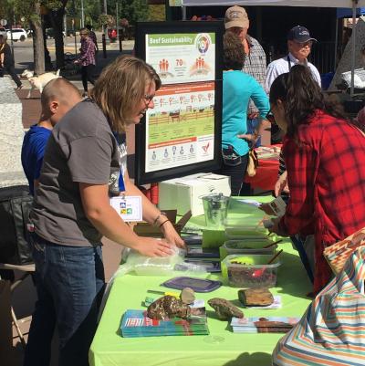 Woman at a booth demonstrating beef sustainability.