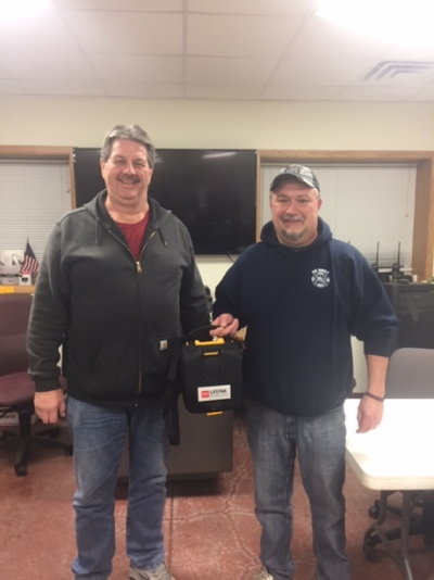 an image of two men holding a donated automated external defibrillator