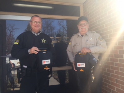 an image of two officers holding donated automated external defibrillators