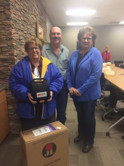 an image of two women and a man with a donated automated external defibrillator