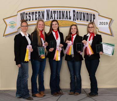4 young women and their coach standing in front of a sign
