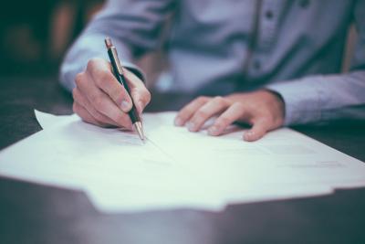 hand holding pen writing on papers