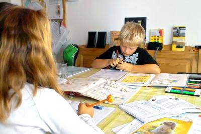 A young male student studying at the kitchen table with an older sister.