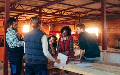 A diverse group of young adults meeting inside a repurposed barn.