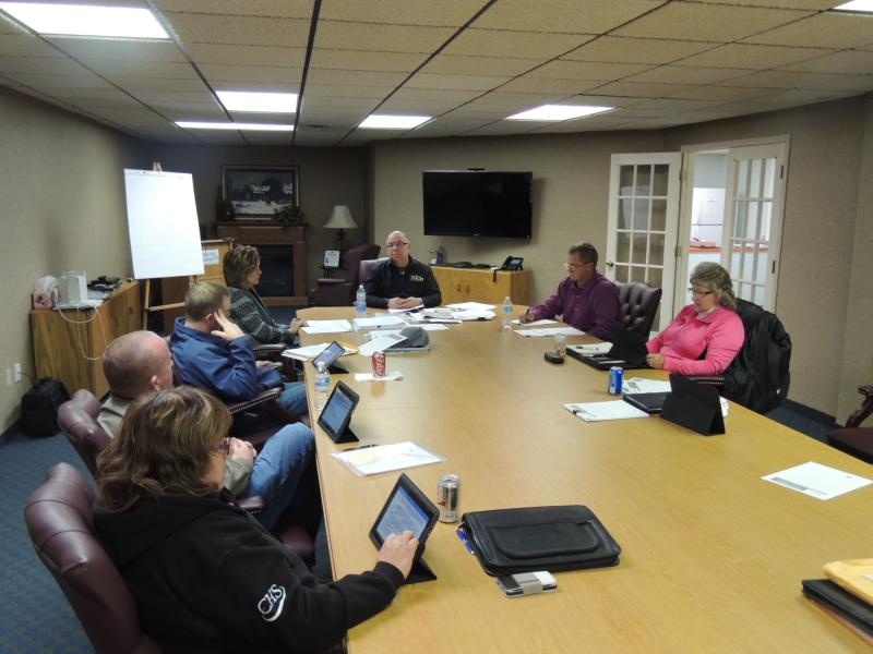 A group of people sitting with ipads around a table.