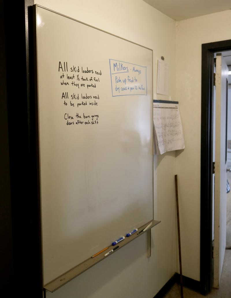 white board mounted on wall with instructions written on it in black and blue marker