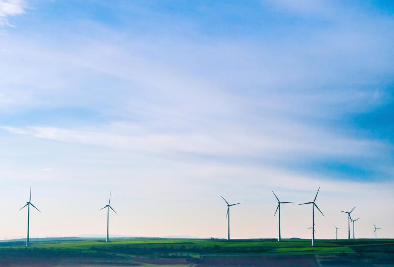several white wind turbines towering above agricultural production land