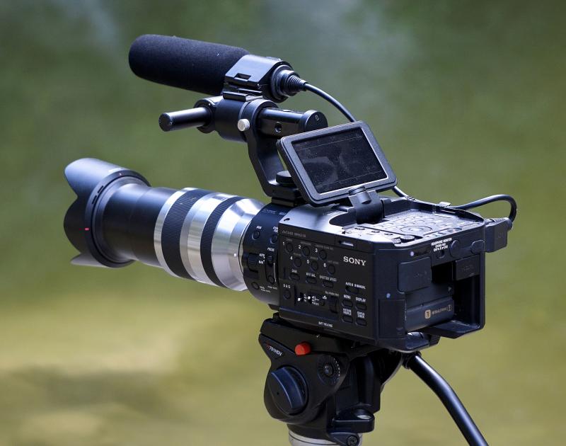 a digital camera with an onboard boom microphone on a tripod.