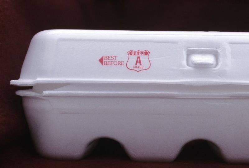 A white egg carton against a black background. The carton has read text reading, "Best Before" along with a red seal reading "USDA 'A' Grade".