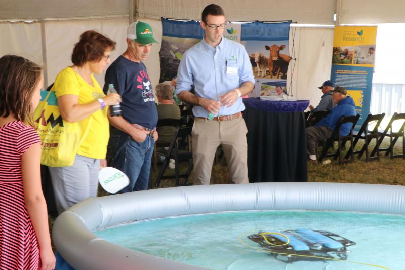 John McMaine, Assistant Professor &amp; SDSU Extension Water Management Engineer, demonstrating an underwater drone in a large pool to a young woman and an older couple.