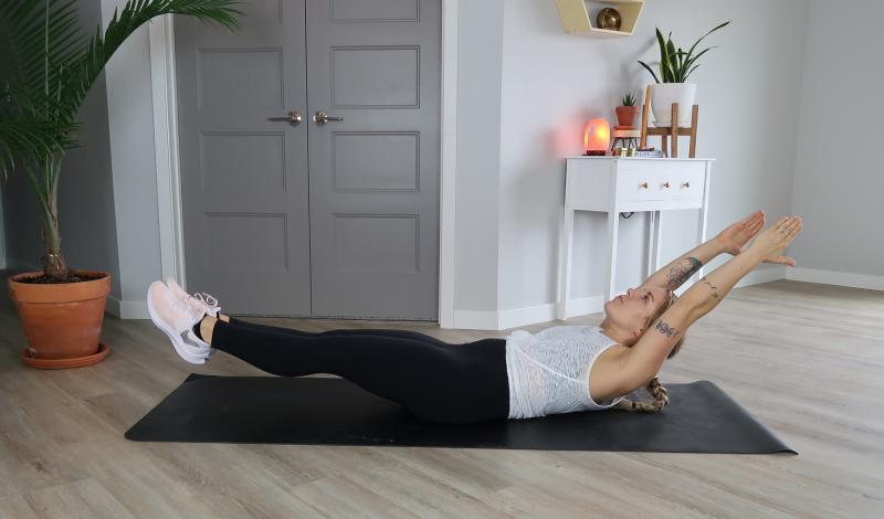 Young woman demonstrating the Hollow Holds core exercise.