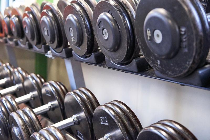 Dumbells sitting on a rack in a gym.