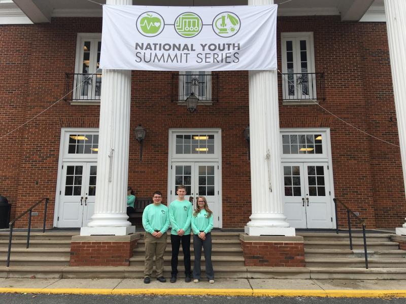 an image of three youth standing in front of a building