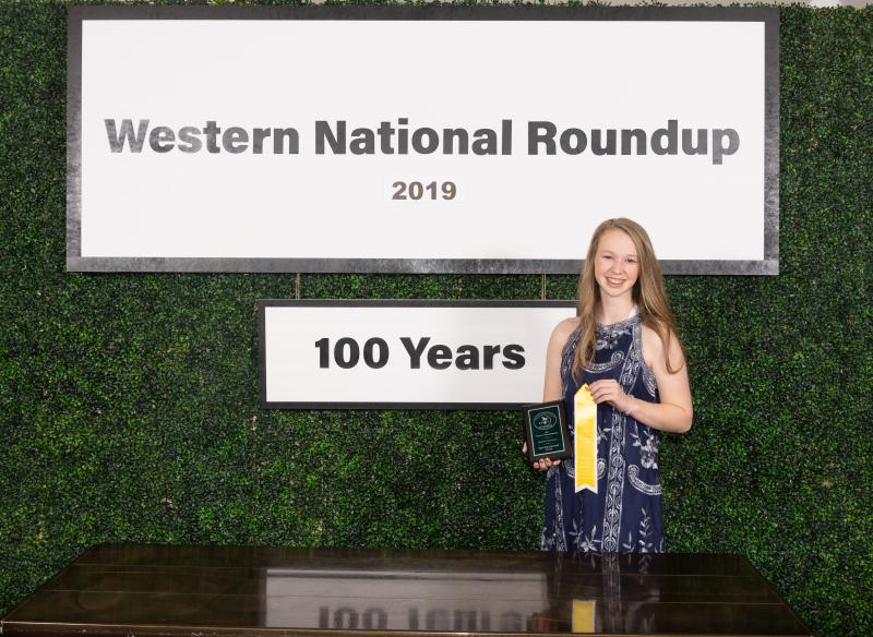a young woman standing in front of a sign with her awards