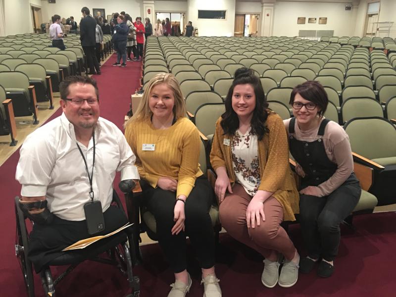 Three woman and a man sitting in an auditorium