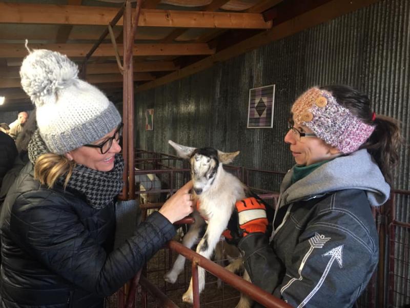 two women holding a small goat.